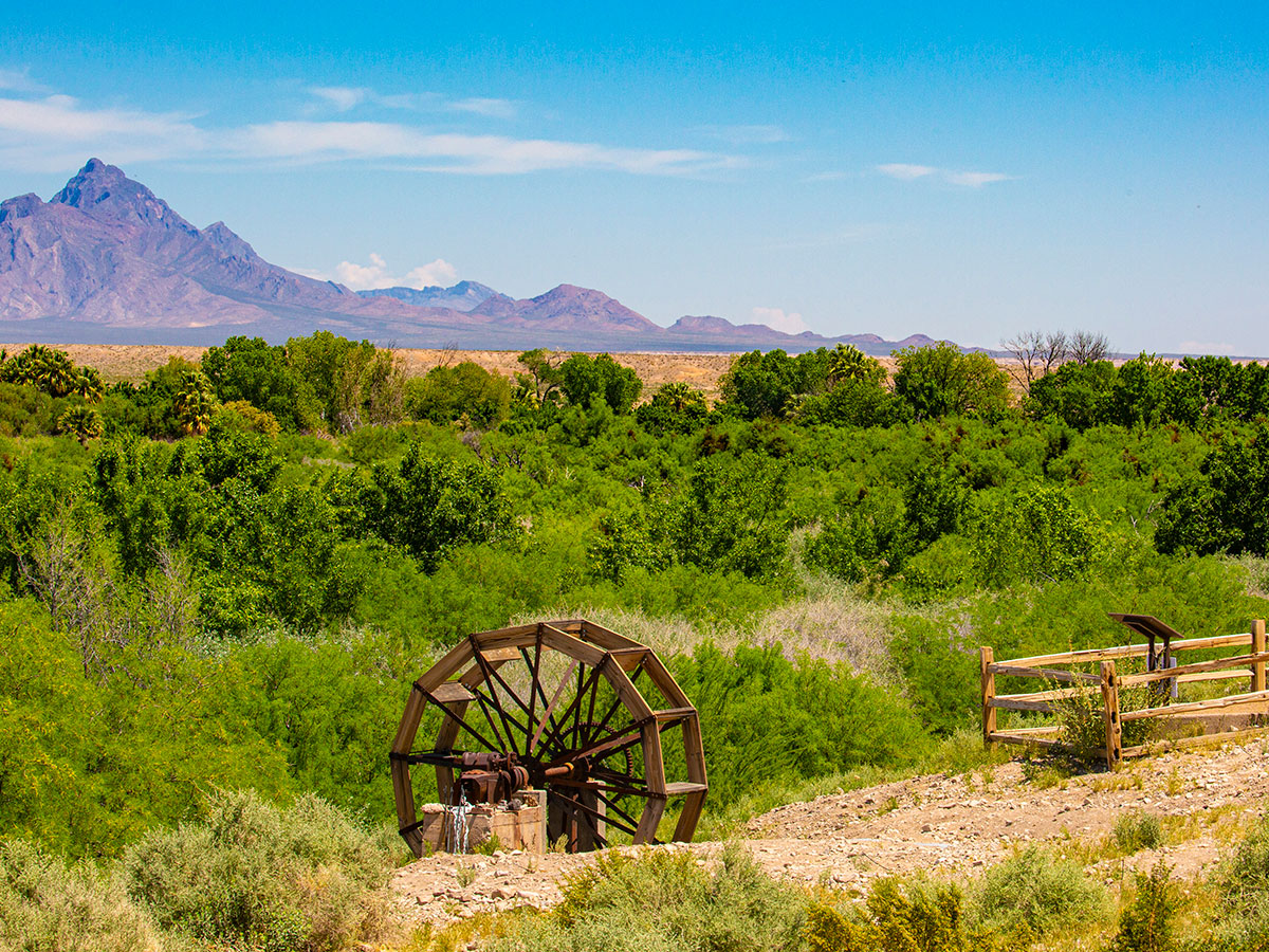 An old water wheel sits in the foreground of the Warm Springs Natural Area